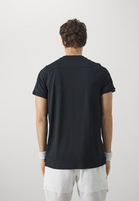 Svart treningstrøye med korte ermer, glatt tekstur og en tettsittende design. Har en subtil sømdetalj over skuldrene.
