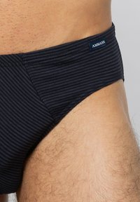 Marinblå randiga simbyxor i ett strukturerat material. Har en sydd midja med en liten etikett. Formad passform med minimal täckning.