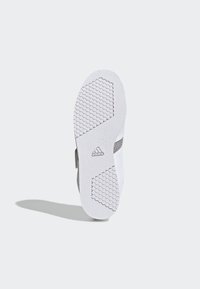 Suela de zapato deportivo blanco con un patrón de tracción hexagonal, que presenta acentos texturizados y un logo cerca del talón.