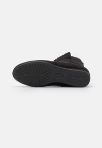 Bottine en daim noir avec semelle en caoutchouc texturée. Dispose d'un bout rond et d'un détail de bord effiloché le long du dessus. Design à semelle plate.