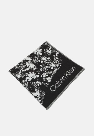 Écharpe noire et blanche avec motif abstrait éclaboussé et logo "Calvin Klein" le long d'un bord, avec des extrémités à franges.