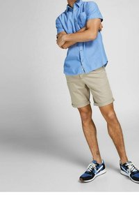 Light blue short-sleeve button-up shirt, khaki rolled shorts, and black athletic shoes with blue accents, featuring a smooth fabric texture.