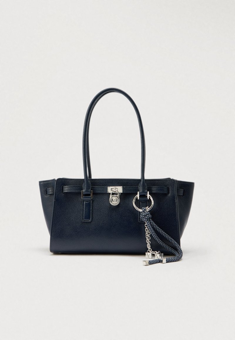 Navy blue leather handbag with textured surface, structured design, dual handles, silver hardware, and a detachable patterned strap.
