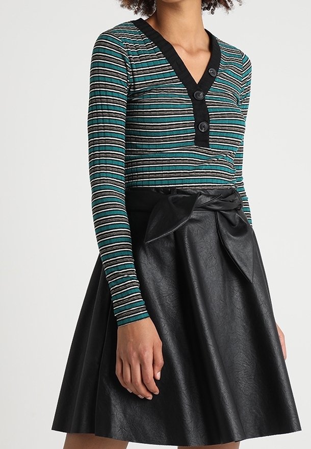 Striped long-sleeve top in teal, black, and white, features a V-neck and three black buttons; paired with a high-waisted black faux leather skirt.