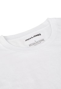 T-shirt bianco in misto cotone e poliestere, con collo a giro e etichetta con marchio, istruzioni per la cura e tag della taglia visibili all'interno del colletto.