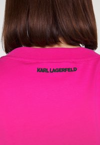 Rosa Baumwoll-T-Shirt mit Rundhalsausschnitt, auf der Rückseite mit schwarzem gesticktem "KARL LAGERFELD"-Detail. Glatte Textur, enganliegendes Design.