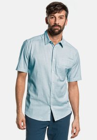 Camisa de botones de manga corta en azul claro con un sutil patrón texturizado, que cuenta con un bolsillo en el pecho y un cuello puntiagudo.