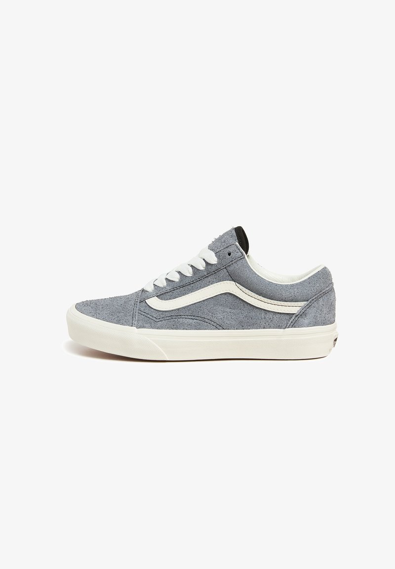 Zapatilla gris de ante con cordones, detalles en cuero blanco y una pestaña en el talón negra. Presenta una puntera redondeada y una suela texturizada.