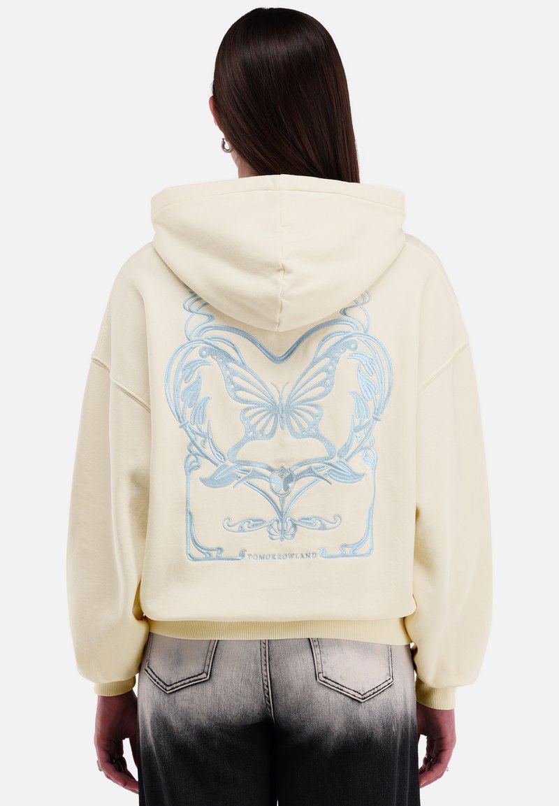 Geknipt geel sweatshirt met capuchon en een blauwe vlinderafbeelding op de achterkant. Zacht materiaal met elastische manchetten en een losse pasvorm.