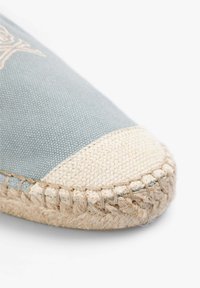 Lichtblauwe canvas espadrille met een natuurlijke vezelzool. Heeft een crèmekleurige geweven teenkap en contrasterende stiksels langs de rand.