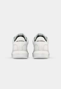 Un par de zapatillas blancas con área del talón texturizada, con la marca "KARL LAGERFELD" en negro en la parte trasera, mostradas desde la vista trasera sobre un fondo blanco.
