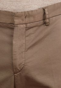Braune Hose aus glattem Stoff mit geradem Schnitt. Verfügt über eine flache Vorderseite, einen Knopfverschluss und seitliche Taschen mit sauberer Naht.
