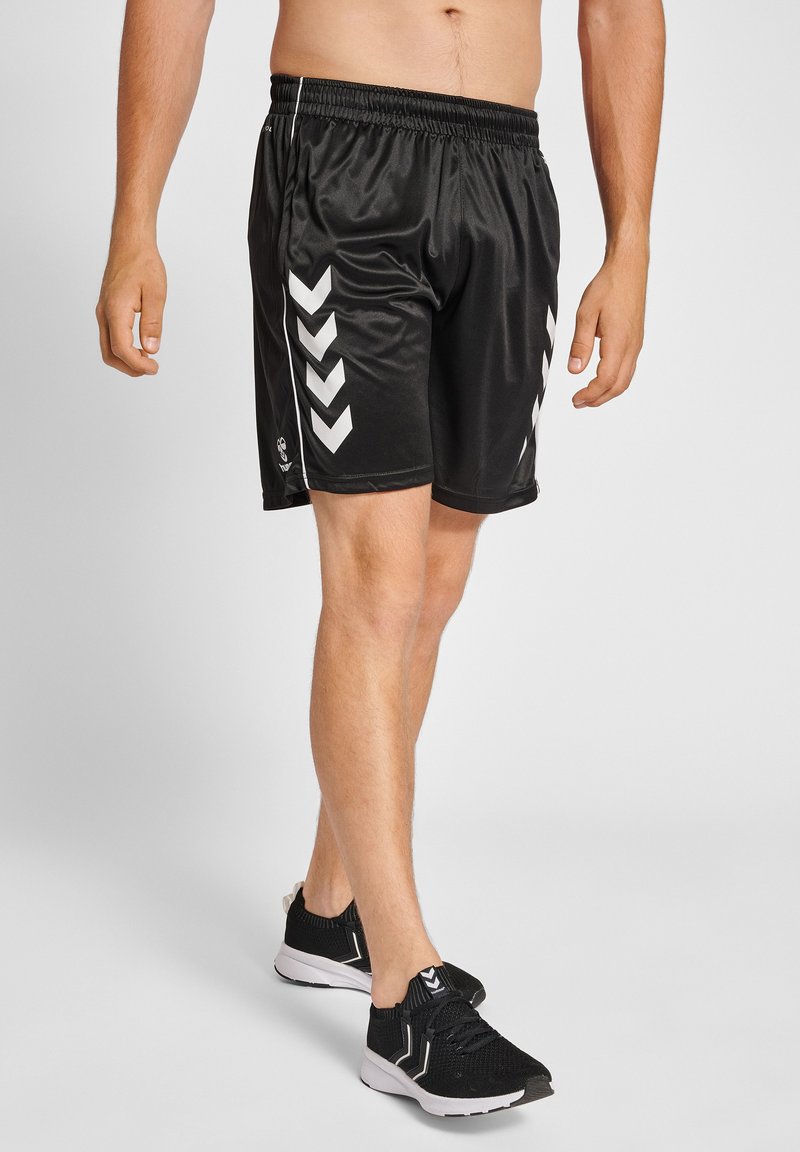 Svarta sportshorts med en blank yta, med vita cheerleader-mönster på sidorna och ett elastiskt midjeband för komfort.