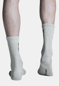 Šviesiai pilkos raukšlėtos kojinės su apvadu viršuje, pasižyminčios glotnia tekstūra ir subtiliu logotipu ant pado. Sukurtos komfortui ir lankstumui.