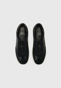 Black athletic shoes made of leather and suede, featuring a textured pattern, round toe, and contrasting white rubber sole; laced design.