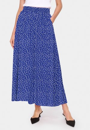 Gonna lunga blu con pois bianchi, vita elastica, tasche laterali, tessuto fluido e silhouette ampia. Abbinata a tacchi neri.