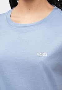 Ανοιχτό μπλε βαμβακερό T-shirt με στρογγυλή λαιμόκοψη, που διαθέτει λευκό κεντημένο λογ�ότυπο "BOSS" στο στήθος και λεία, απαλή υφή.