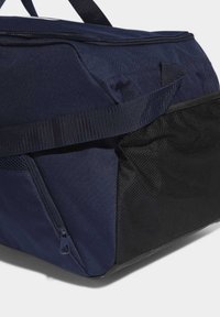 Tmavě modrá taška přes rameno s texturovaným povrchem, kapsou na zip a síťovinovým akcentem. Obsahuje robustní držadla a široký otvor pro snadný přístup.