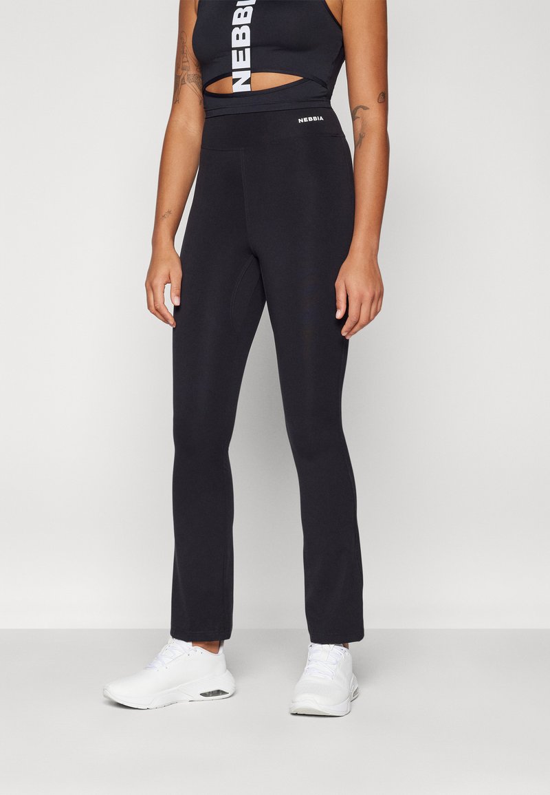 Black high-waisted leggings in a smooth, stretchy material, featuring a logo at the waistband, styled with white sneakers.