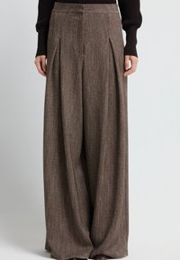 Pantaloni larghi marroni, texturizzati, con pieghe davanti e vita su misura, realizzati in un tessuto misto lana.