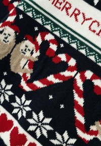 Maglione in maglia con sfondo blu navy, decorato con bastoncini di zucchero, fiocchi di neve e orsi in beige e rosso. Incluso il testo "Buon Natale".