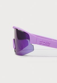 Fioletowe okulary przeciwsłoneczne sportowe z solidną oprawką i ciemnymi soczewkami. Charakteryzują się kanciastym wzornictwem oraz logo na ramieniu.
