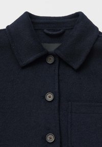Navy wool shirt jacket with a collared neck, three dark buttons, and a chest pocket. Soft texture with a smooth inner lining.