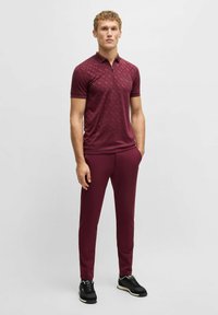 Bordowy polo z delikatnym wzorem, krótki rękaw i zamek błyskawiczny przy kołnierzyku, połączony z dopasowanymi spodniami slim fit i czarnymi sneakersami.