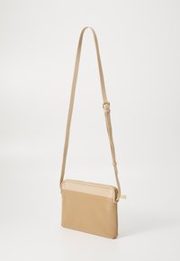 Beige Umhängetasche mit rechteckiger Form, glattem Leder, Reißverschluss und verstellbarem Tragegurt. Minimalistisches Design mit dezenten Akzenten.
