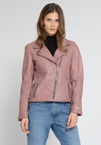 Veste de biker en cuir rose avec une coupe ajustée, fermeture éclair asymétrique, quincaillerie argentée et deux poches zippées. Associée à un jean taille haute.