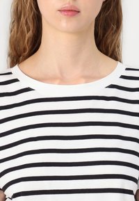 Black and white striped t-shirt featuring a round neckline and short sleeves, made from a soft cotton blend with a smooth texture.