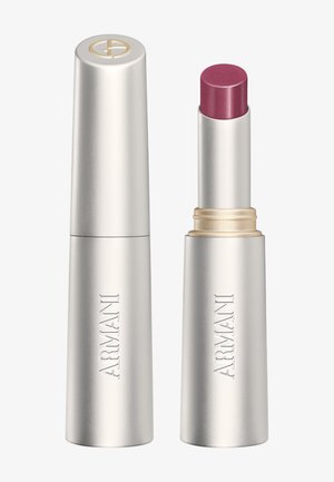 Tube de rouge à lèvres Armani argenté avec le capuchon posé à côté, montrant le bâton de rouge à lèvres rose rougeâtre étendu.