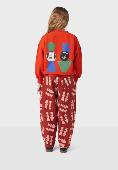 Rode sweatshirt met abstracte karakterontwerpen en gestreepte rode broek met lichte figuren. Casual, ontspannen pasvorm met een levendige uitstraling.