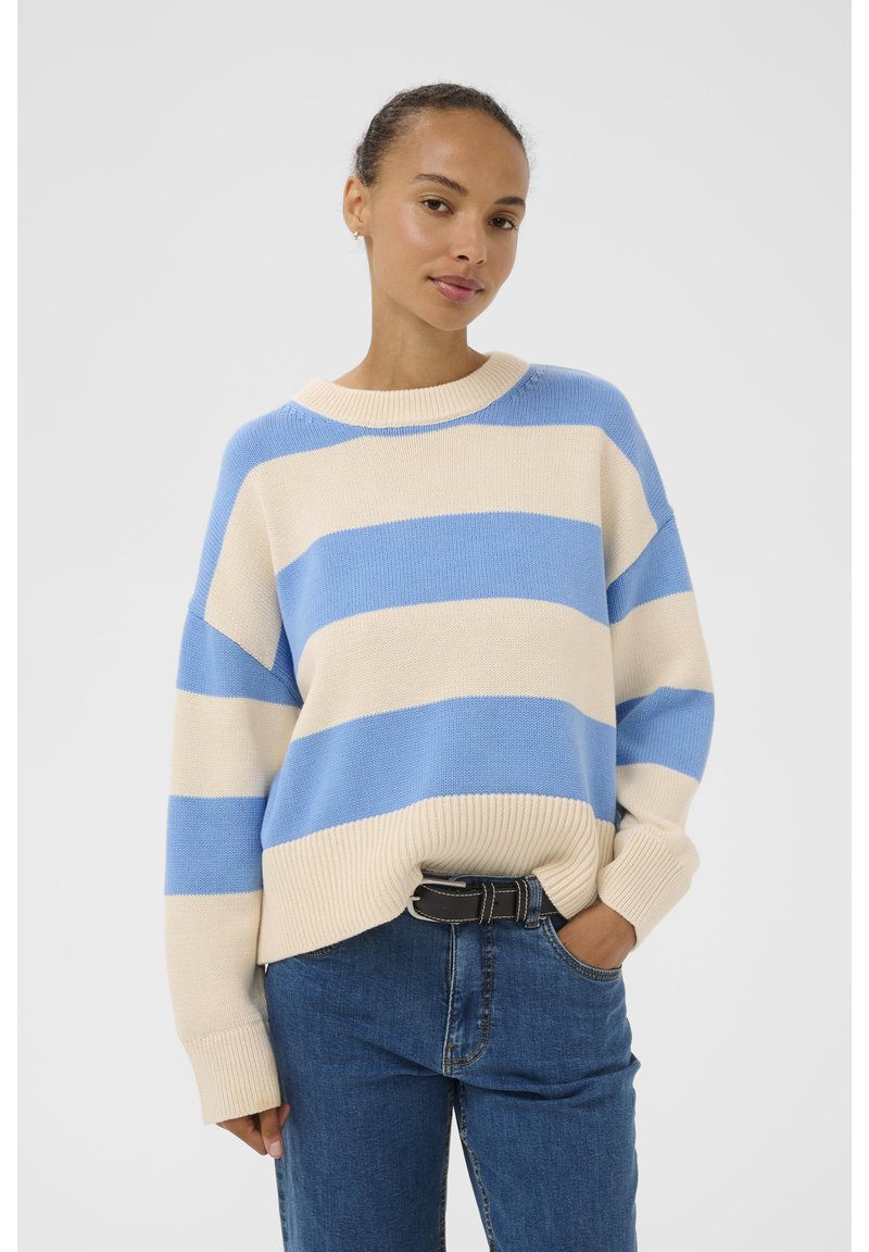 Pulover striped în crem și albastru deschis, textură tricotată, croială lejeră, guler rotund, asortat cu blugi și o curea neagră.