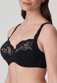 Black bra featuring a checkered pattern, floral lace detailing at the top, adjustable straps, and a bow accent in the center.