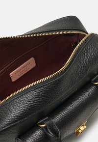 Borsa in pelle nera con superficie texturizzata e accessori in oro. L'interno presenta una fodera bordeaux e un'etichetta in pelle. Chiusura con zip visibile.