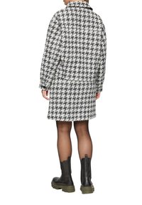 Jasje en rok van een houndstooth-patroon, textiel in zwart en wit, gecombineerd met zwarte en groene enkellaarsjes.