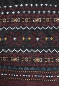 Strickstoff mit horizontalen nordischen Mustern in Schwarz, Burgunderrot, Weiß, Gelb und Blau, einschließlich geometrischer und Stern-Motive.