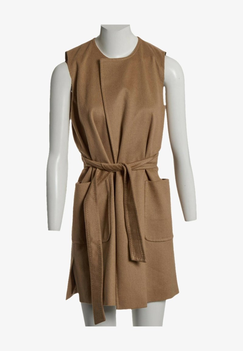 Robe ceinturée marron camel sans manches avec deux poches avant sur un buste de mannequin blanc.