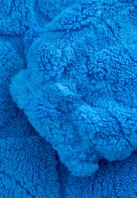 Tissu en polaire bleu, texture douce, avec une surface dense et duveteuse présentant des hauteurs de poil variées et une couleur uniforme et vibrante.