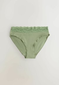 Jasnozielona damska bielizna z koronkowym paskiem, bezszwowa krawędź i gładki materiał, rozłożona na jasnej powierzchni.