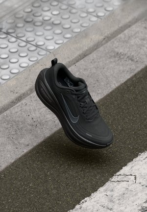 Black athletic shoe with mesh upper, rounded toe, and padded collar. Features a grey swoosh and "ZOOMX" branding on the midsole.