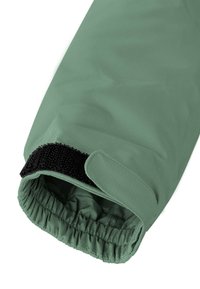 Grüner Stoffärmel mit strukturierter Oberfläche. Elastischer, geraffter Öffnung und schwarzem Klettverschluss für den Verschluss. Einfaches, funktionales Design.
