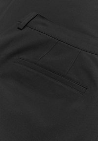 Svarta byxor med en slät tygstruktur och en enda bakficka. Fickan är enkel och har en smal, sydd kant.