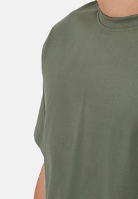 Kurze Ärmel T-Shirt in Olivgrün, aus weicher Baumwolle gefertigt. Es hat einen Rundhalsausschnitt und eine entspannte Passform mit minimalen Nähten und Verzierungen.