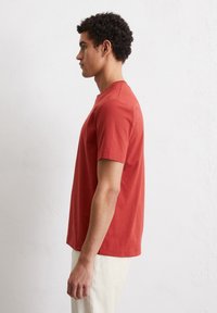 Red cotton t-shirt with short sleeves, crew neckline, and a relaxed fit, displayed on a model against a neutral background.