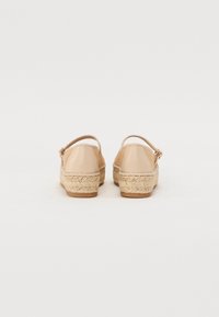 Nude-fargede espadriller med en flettet jutesåle og en glatt, avrundet bakside. Har en slingback-design med en liten spenne detalj.