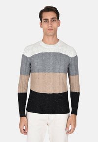 Maglione lavorato a maglia con un design a blocchi di colore in bianco, grigio, beige e nero. Polsini a costine e scollatura rotonda. Motivi testurizzati visibili.