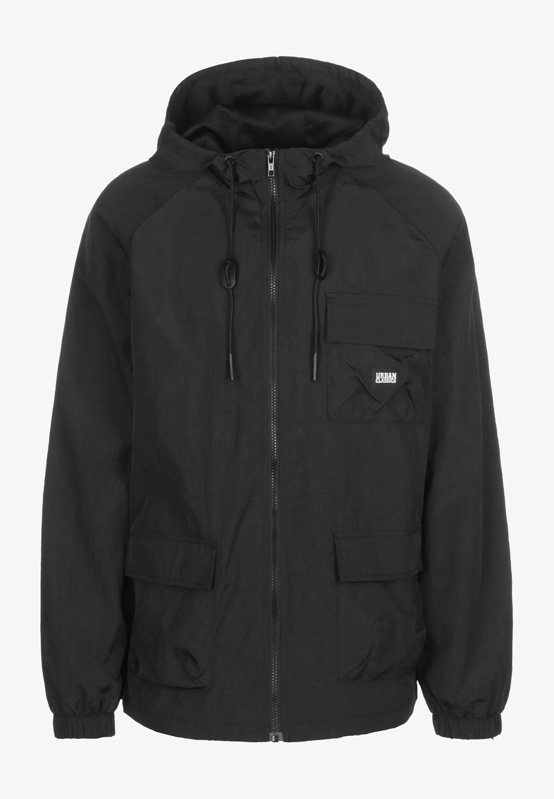 Veste à capuche noire avec une fermeture éclair, deux poches avant et une poche sur la poitrine. Fabriquée en matériau léger; dotée de cordons de serrage et de poignets élastiques.