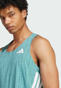 Hellblauer sportlicher Tank-Top mit strukturiertem Muster, weißen Schulterakzenten und einem Logo auf der oberen linken Seite.